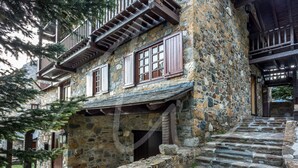 A stone building with wooden balconies and a staircase leading to the entrance.