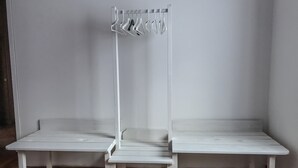 Une pièce avec deux bancs blancs et un porte-manteau muni de plusieurs cintres.