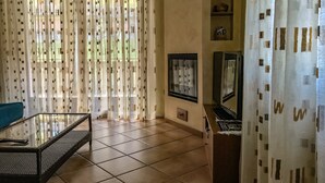 Un salon avec une table basse en verre, un canapé, un téléviseur et un meuble.
