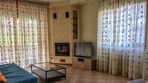 Un salon avec un canapé, une table basse en verre, un téléviseur et une cheminée.
