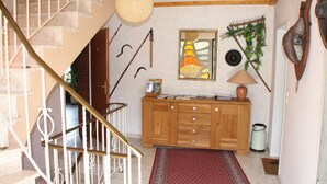 A staircase with white balusters, a wooden cabinet with drawers, a hanging lamp, and a framed picture on the wall. - Haus Buchholz Apartment 3   (Liesenich)