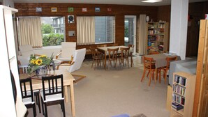 A cozy living room with a dining area, a bookshelf, and a window with curtains. - Haus Buchholz Apartment 3   (Liesenich)