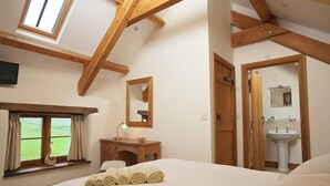 Een slaapkamer met een groot bed, een houten bureau, een spiegel en een raam met gordijnen.
