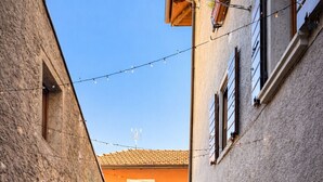 A narrow alley with stone flooring, a table with chairs, and a building with a tiled roof. - La Rotonda Vigneto Apartment (Tremosine)