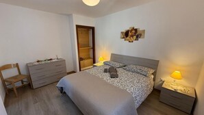 A bedroom with a bed, bedside tables, a dresser, a chair, and a wardrobe. - La Rotonda Vigneto Apartment (Tremosine)