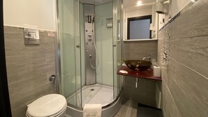 Un baño moderno con ducha de vidrio, inodoro y tocador con lavabo.
