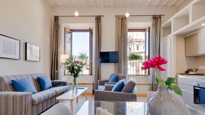 A modern living room with a sofa, armchair, and coffee table. There is a vase with flowers on the table. - Grotta Pinta 11 | Bright and spacious in the center of Rome (Roma)