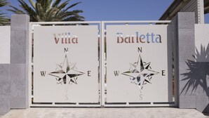 A gate with two signs, one labeled "Villa" and the other "Bailetta," each featuring a compass rose. - Villa Barletta apartment in villa ground floor n.1 (Marina di Acate)