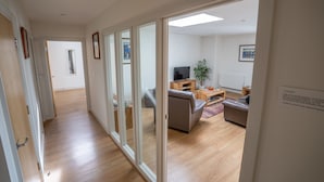 A modern living room with a sofa, TV, and wooden flooring. - Very popular modern 2 bedroom apartment sleeps 4  located opposite Deal Pier.   (Deal)
