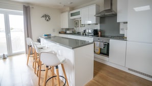 A modern kitchen with a central island, white cabinetry, and a built-in oven. - Very popular modern 2 bedroom apartment sleeps 4  located opposite Deal Pier.   (Deal)
