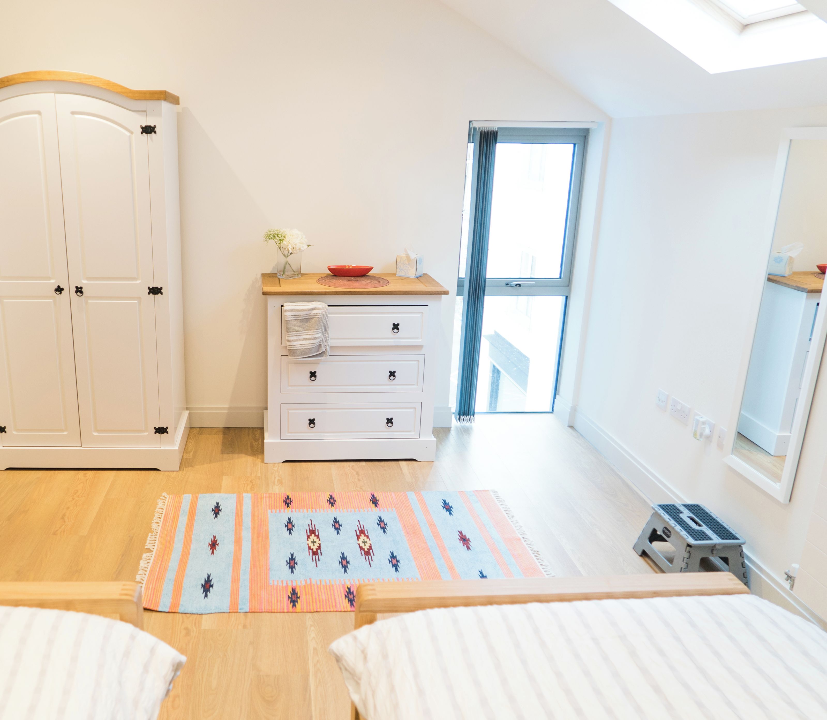 A second bedroom with two beds, a wardrobe, a dresser, and a window.