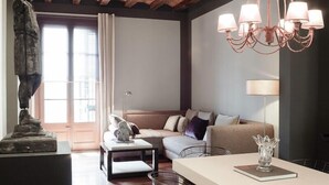 A modern living room with a stone statue, a sofa, a coffee table, and a chandelier.