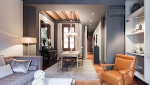 A modern living room with a sofa, armchair, and a dining table with chairs.