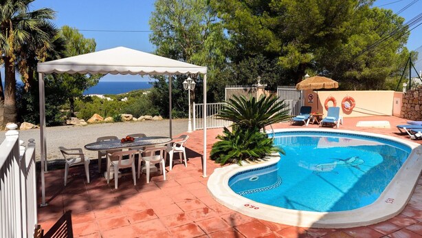 Piscina com borda curva, rodeada por um terraço com cadeiras e mesa.
