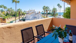 A balcony with two chairs, a table, a potted plant, and a bottle of wine. - Apartment only 80 Meters from the Beach (Marbella)