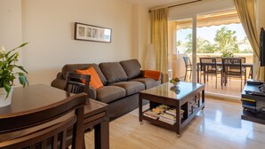 A living room with a sofa, coffee table, and dining area. - Apartment only 80 Meters from the Beach (Marbella)