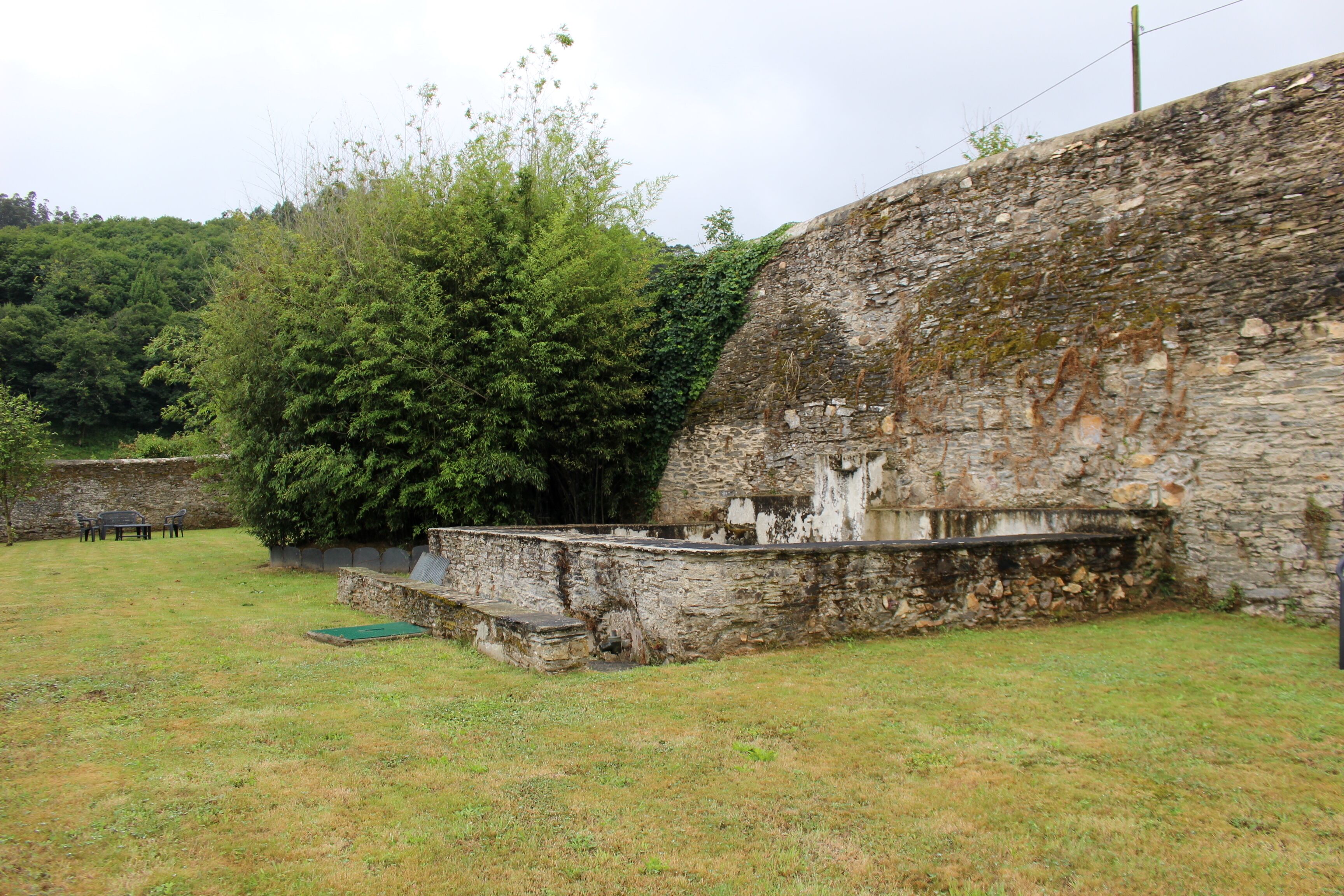 Un muro de piedra con un área verde al frente.