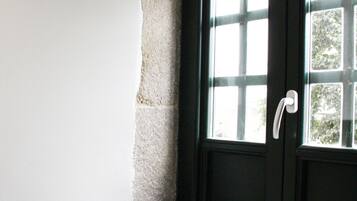 Una puerta negra con manija blanca, una ventana con múltiples vidrios y un alero de piedra.