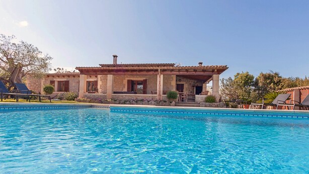 A poolside view of a stone building with a tiled roof, surrounded by a pool and lounge chairs. - Villa Tatoli is a spacious and traditional 4 bedroom villa with private pool (Pollensa)