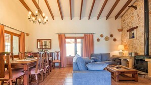 A cozy living room with a sofa, dining table, chairs, and a fireplace. - Villa Tatoli is a spacious and traditional 4 bedroom villa with private pool (Pollensa)