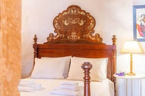 A neatly made bed with a wooden headboard, white pillows, and folded towels.