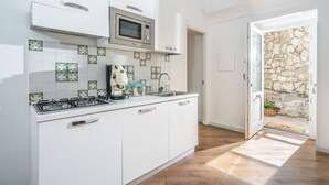 Une cuisine moderne avec des armoires blanches, un four à micro-ondes encastré et une cuisinière à gaz.