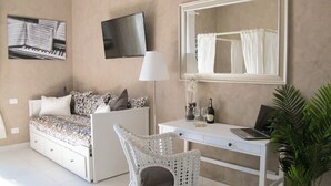 A bedroom with a bed, a desk, a chair, a TV, and a mirror.