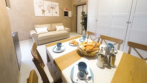 A dining area with a wooden table set for two, a beige sofa, and a wall-mounted artwork.