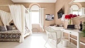 A bedroom with a four-poster bed, a desk with a laptop, a chair, and a large mirror.