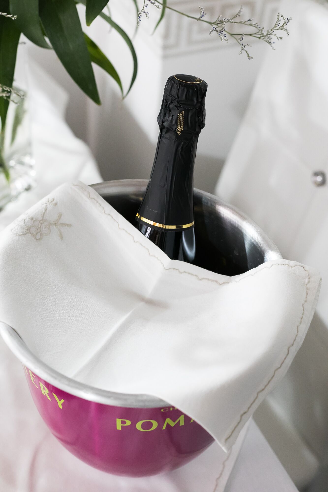 A champagne bottle in a pink and white bucket with a white cloth cover.