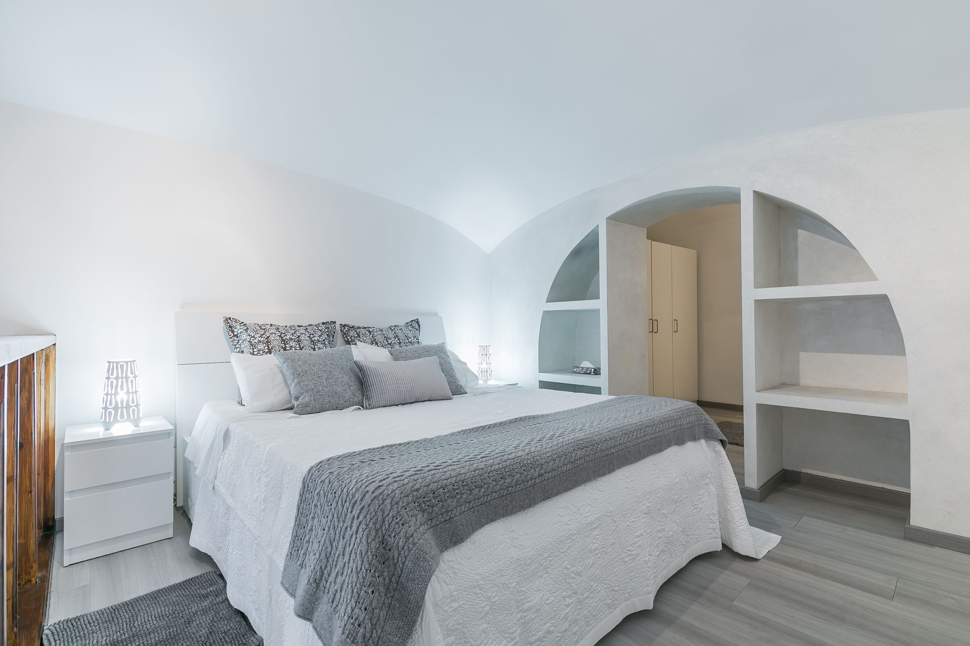 Ein modernes Schlafzimmer mit einem großen Bett, weißen Wänden und einer gewölbten Decke.
