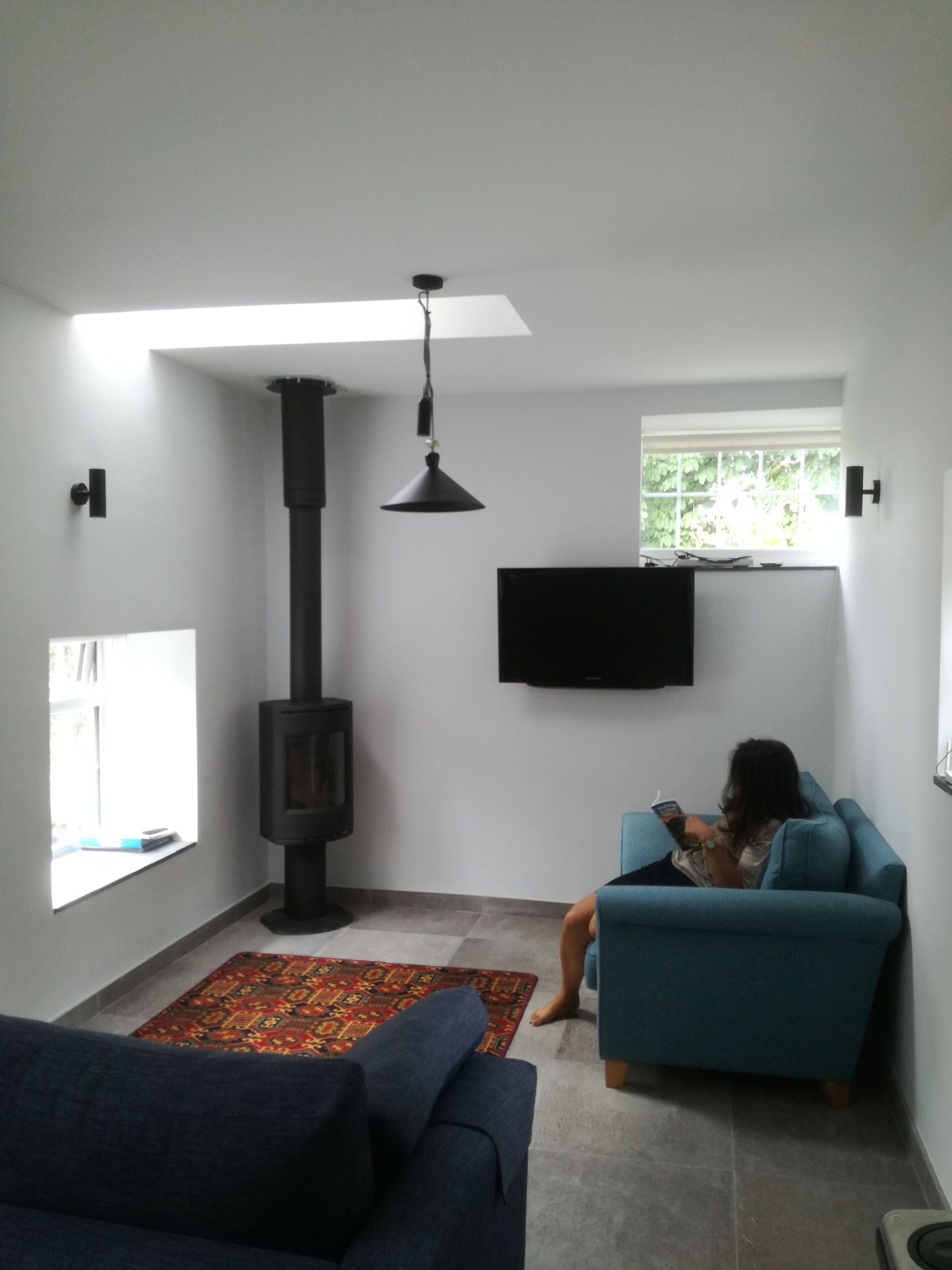 Ein Wohnzimmer mit Kamin, einer Couch, einem Fernseher und einer Person beim Lesen.