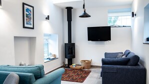 A modern living room with a fireplace, two sofas, a television, and a large window.