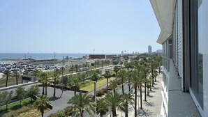 A view of a parking lot with palm trees and a building with large windows. - Sea view three bedroom apartment - You Stylish (Barcelona)