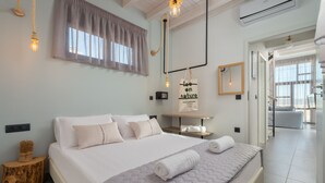 A modern hotel room with a large bed, a bedside table, a mirror, and a view of the hallway.