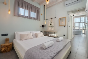 A modern hotel room with a large bed, a bedside table, a mirror, and a view of the hallway.