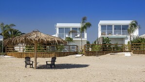 A beachside property with a thatched umbrella, two chairs, and a wooden fence.
