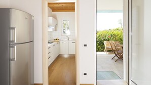 A modern kitchen with white cabinets, a stainless steel refrigerator, and a wooden ceiling.