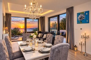 A dining area with a table set for four, a chandelier, and a painting on the wall. - Modern holiday house Anja with heated pool and sea view, 3 bedrooms 6+2 pers. (Makarska)