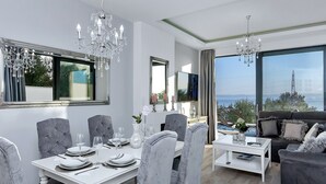 Un salon moderne avec un coin repas, de grandes fenêtres et une vue sur la mer.