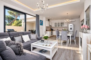 A modern living room with a grey sofa, a coffee table, and a chandelier. - Modern holiday house Anja with heated pool and sea view, 3 bedrooms 6+2 pers. (Makarska)