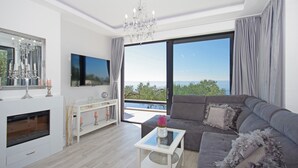 Un salon moderne avec une cheminée, un grand téléviseur et une vue sur la mer.