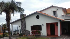 A house with a stone facade, a red door, and a paved driveway.