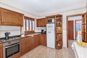 A kitchen with wooden cabinets, a stove, an oven, a microwave, and a refrigerator.