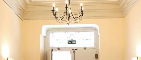 L’entrée d’un hôtel, avec un lustre, une enseigne indiquant « SORTIE » et un paillasson.