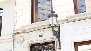 Un edificio con un puerta doble de madera, una farola y un cartel con el número 10.