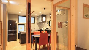 A modern kitchen with a dining area, featuring a black refrigerator, wooden cabinets, and a glass door leading to a staff-only area.