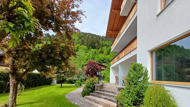 A modern house with a stone pathway leading to a wooden deck, surrounded by lush greenery and a hillside. - Panorama App 2C am See, für 2-4,free WIFI (Zell am See)