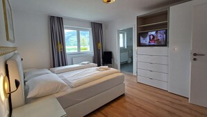 A bedroom with a bed, a TV on a stand, a wardrobe, and a window with curtains. - Panorama App 2C am See, für 2-4,free WIFI (Zell am See)