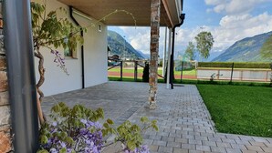 A covered outdoor area with a brick floor, a stone pillar, and purple flowers. - Panorama App 2C am See, für 2-4,free WIFI (Zell am See)